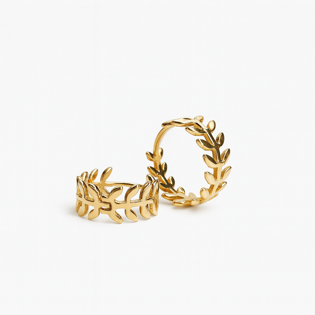 Two gold rings featuring a leaf pattern sit against a plain white background. Their intricate design conveys elegance and a nature-inspired theme.
